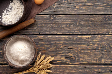 Poster - flour in a wooden bowl on dark wooden background