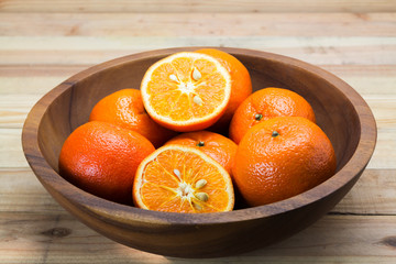 Wall Mural - Fresh oranges in wooden bowl. On a wooden background.