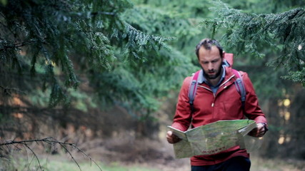 young, lost man with a map looking for direction in forest