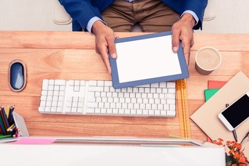 Poster - Creative businessman holding digital tablet while sitting at des