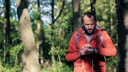 Wall Mural - a lost young man with smartwatch looking for direction in the forest