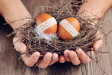 Nest of Easter eggs in the hands on a wooden background