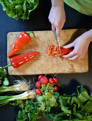  Female slicing pepper for salad. Close up chef cutting vegetabl