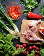 Young woman preparing chicken with vegetables