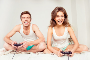 Canvas Print - Cute couple in love playing video games with joysticks on the be