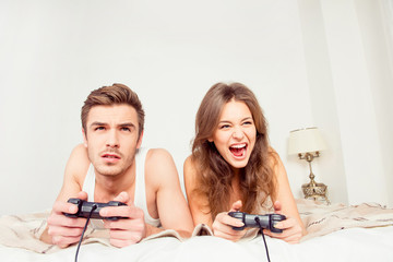 Canvas Print - Happy couple in love playing video games with joysticks on the b