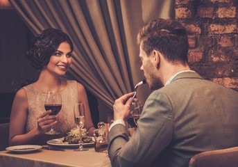 Wall Mural - Stylish wealthy couple enjoying meal at restaurant.