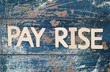 Pay rise written with wooden letters on rustic surface
