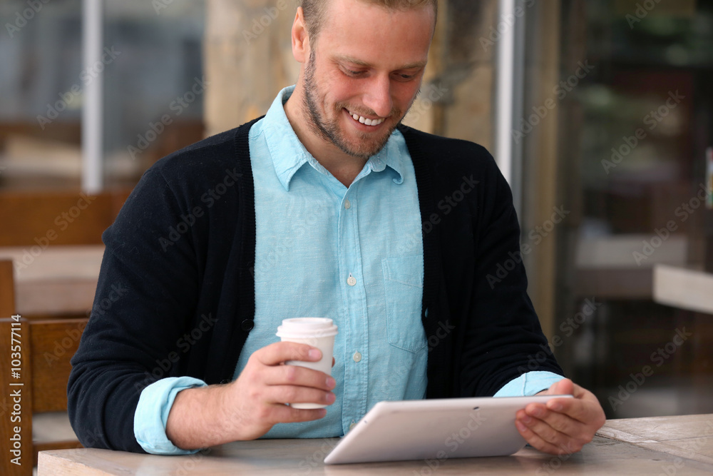 Young attractive businessman having lunch and working in a cafe