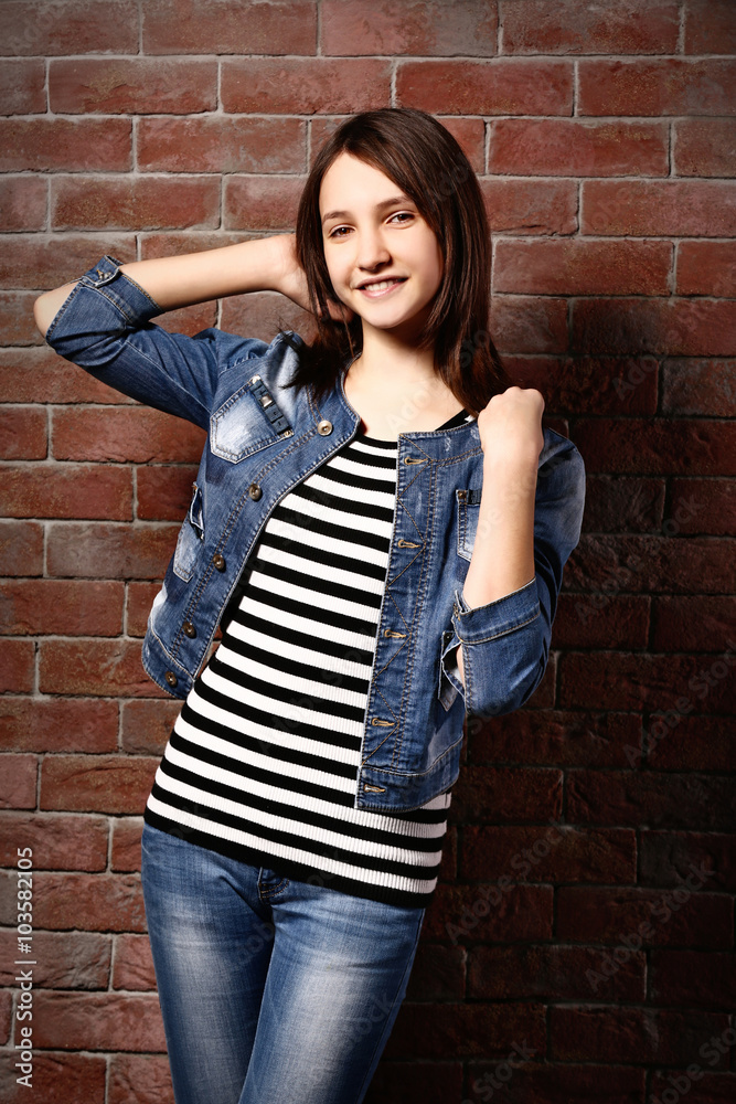 Beautiful young girl posing on brick background