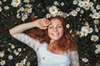 Leinwandbild Motiv Beautiful young girl with curly red hair in chamomile field