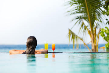 Brunette girl with cocktails in swimming pool