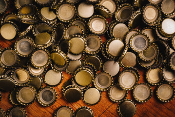 Large pile of beer bottle caps on wooden desk