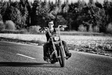 Tough, Tattooed Biker With His Chopper In Motion On The Road