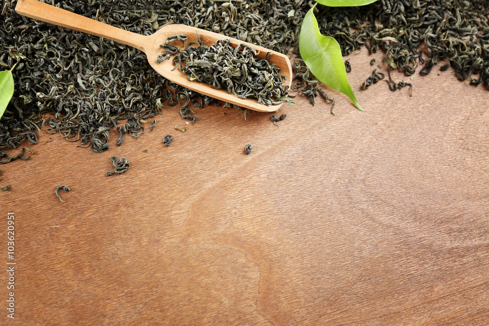Scattered tea with green leaves on wooden table background, copy space