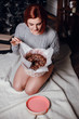 © Olena_Molchanova - fashion interior photo of beautiful young woman with red hair and charming smile, wears cozy knitted cardigan, posing beside Christmas tree and presents with chocolate cake with asterisks