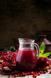 Jug with fresh pomegranate juice on the background of open grena