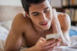 © theartofphoto - Handsome young man in bed typing on cell phone