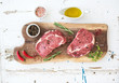 Raw fresh meat Ribeye steak entrecote and seasonings on cutting board over white wooden background.