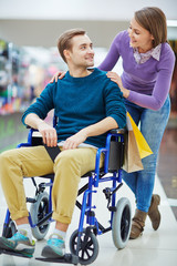 Canvas Print - Pretty girl talking to her boyfriend in wheelchair during shopping