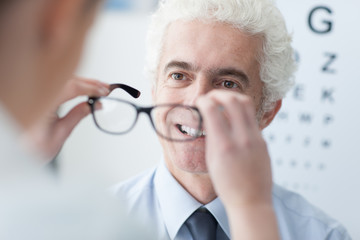 Optician giving new glasses to the patient