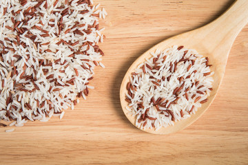 scoop of brown rice and a pile of brown rice on the wood backgro