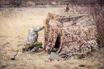 Man installing hunting tent in rural field   