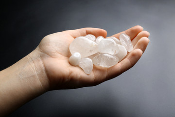 Poster - Woman holding semiprecious stones in her hand on dark grey background