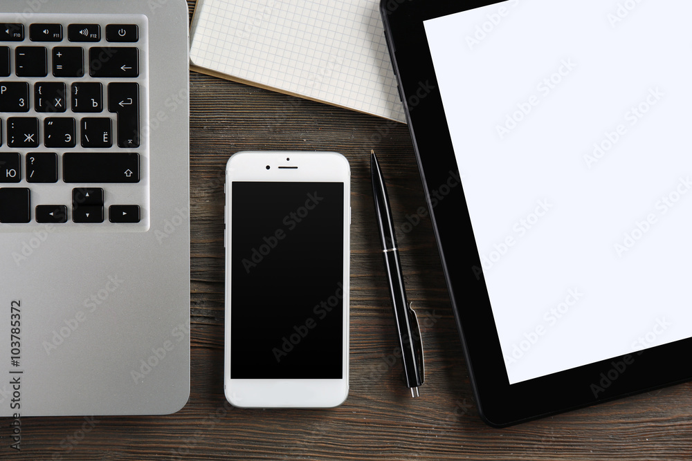 Modern laptop, tablet, mobile phone and notebook on the table, close-up