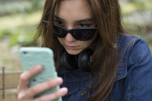 若い女性はサングラスをずらして携帯電話を見ている Stock Photo Adobe Stock