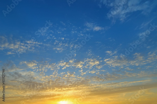 Obraz w ramie Background photo of natural Clouds formation on a blue sky in the evening with yellow shade of the sun