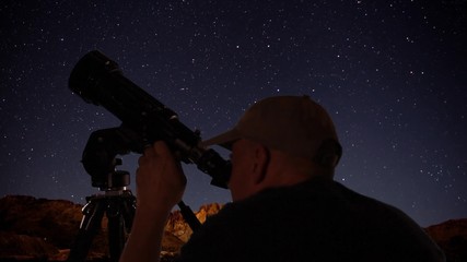 Wall Mural - an astronomer viewing space objects through a telescope