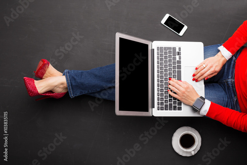 Fotografie, Obraz Woman sitting on ground at the office with computer in her lap