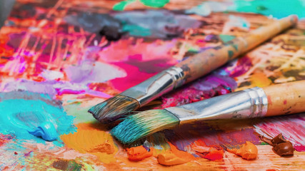 Used brushes on an artist's palette of colorful oil paint