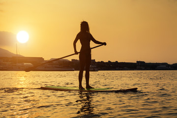 Wall Mural - Silhouette of a beautiful woman on Stand Up Paddle Board. SUP.