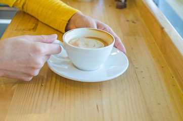 Wall Mural - hand holding white coffee cup on wood table in coffee cafe