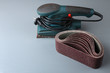 Vibratory sander with sandpaper on grey wooden table
