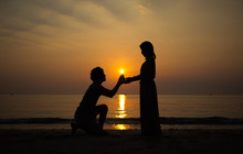 A Backlit Man Propose Marriage To A Backlit Woman With Sunrise Background