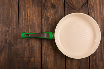 Ceramic Frying Pan on wooden background, top view