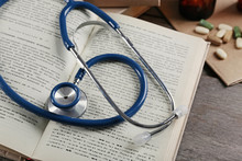 Book, Pills And Stethoscope On Wooden Table Closeup