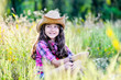 © sushytska - little girl sitting in a field wearing a cowboy hat