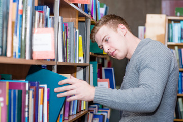 Wall Mural - male student chooses a book in the library