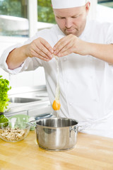 Wall Mural - Chef cracking egg in large kitchen