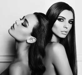 Wall Mural - fashion studio photo of two beautiful young women with dark hair, posing together