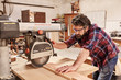 © mavoimages - Carpenter using radial arm saw to cut wood in workshop