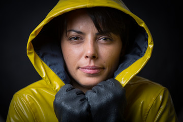 Wall Mural - Attractive young woman posing with a yellow raincoat