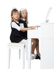 Wall Mural - Two girls of preschool age diligently play the piano - Isolated on white background