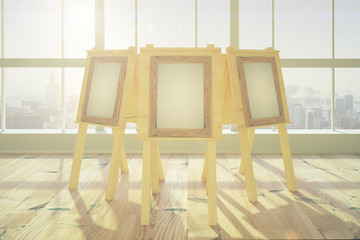 Wall Mural - Blank picture frames on easels in big sunny room with wooden flo