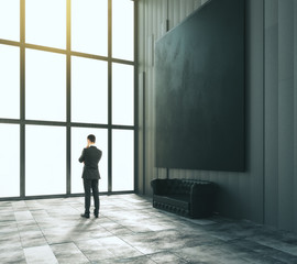 Aufkleber - Businessman in loft room with blank black big picture, leather s