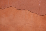 Fototapeta Dmuchawce - Old terracotta painted stucco wall with cracked plaster. Backgro
